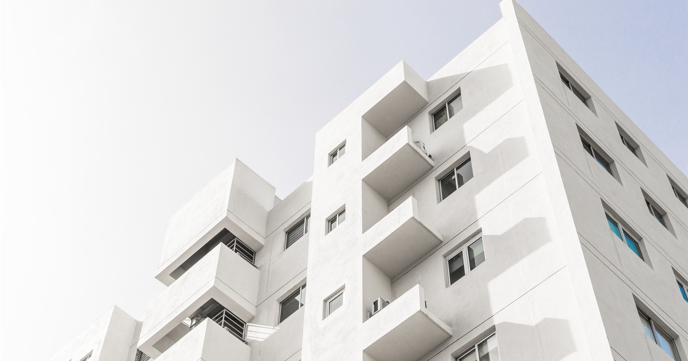 low-angle-shot-facade-white-modern-building-blue-clear-sky X X